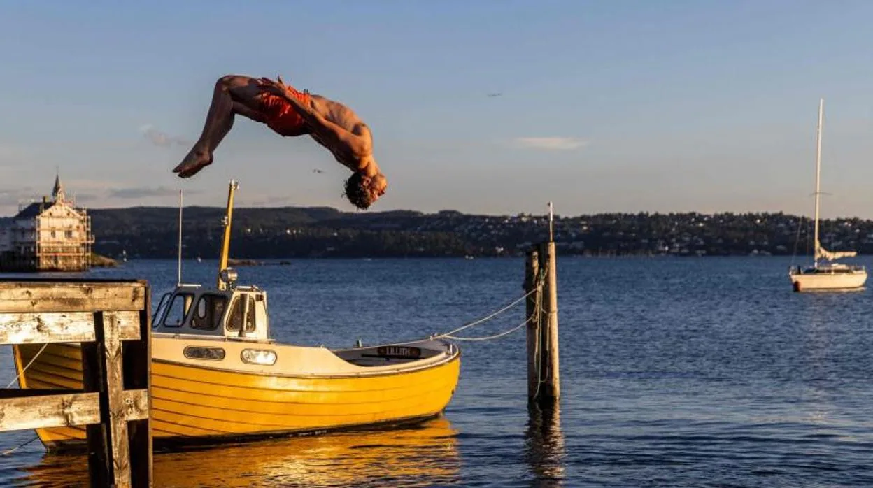 Un hombre da un salto mortal al fiordo para nadar por la noche en la isla Lindoya en Oslo