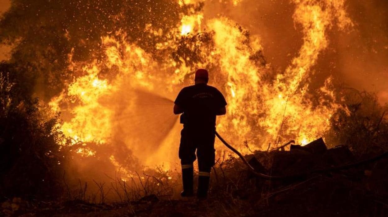 Un bombero intenta extinguir un incendio forestal en el pueblo de Pefki, en la isla de Evia, Grecia