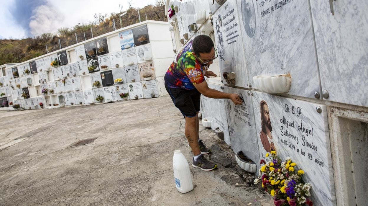 José Alejandro, empleado de la funeraria local, limpia una lápida en el cementerio de Las Manchas