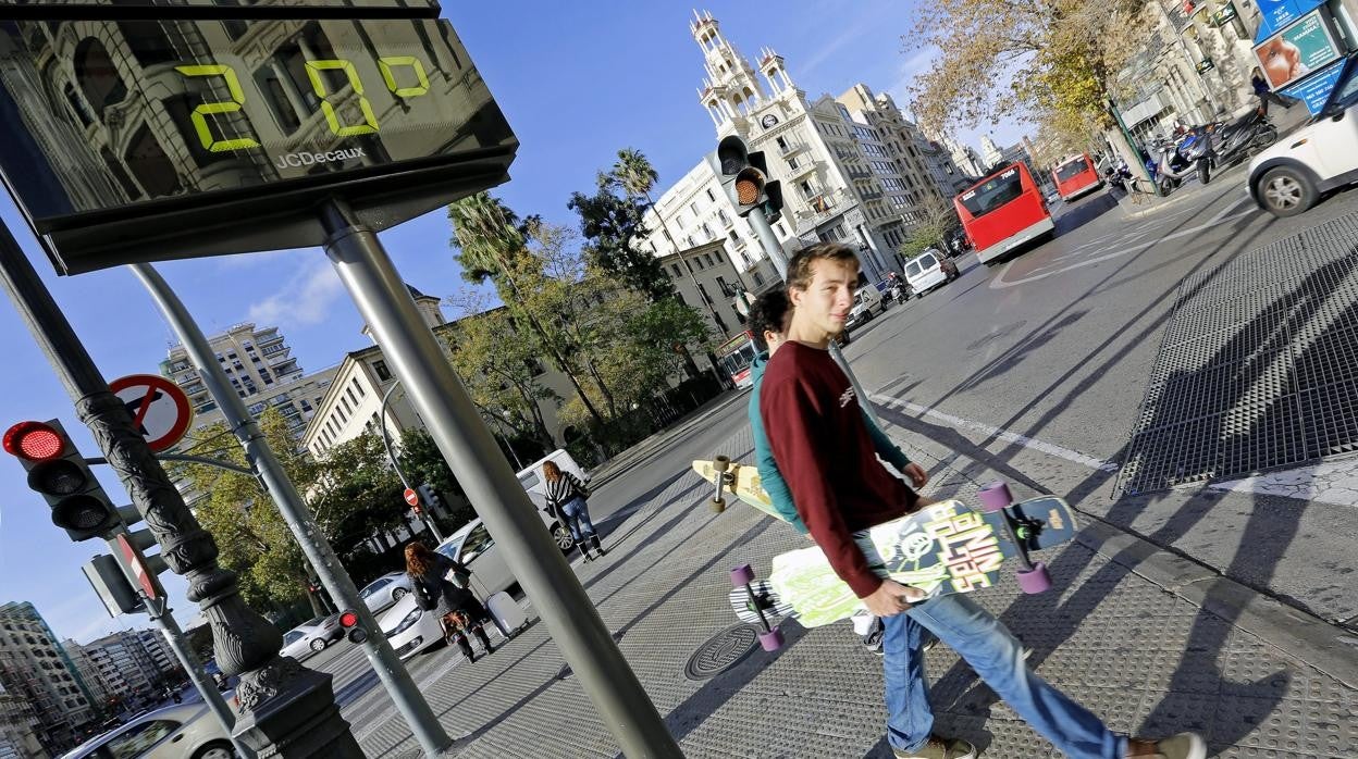 Dos jóvenes pasan por debajo de un termómetro que marca 20 grados