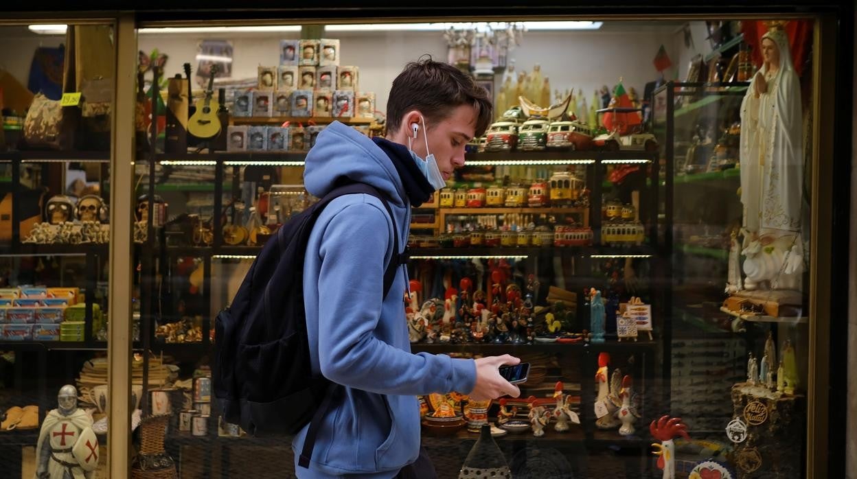 Un joven con mascarilla pasea por Lisboa