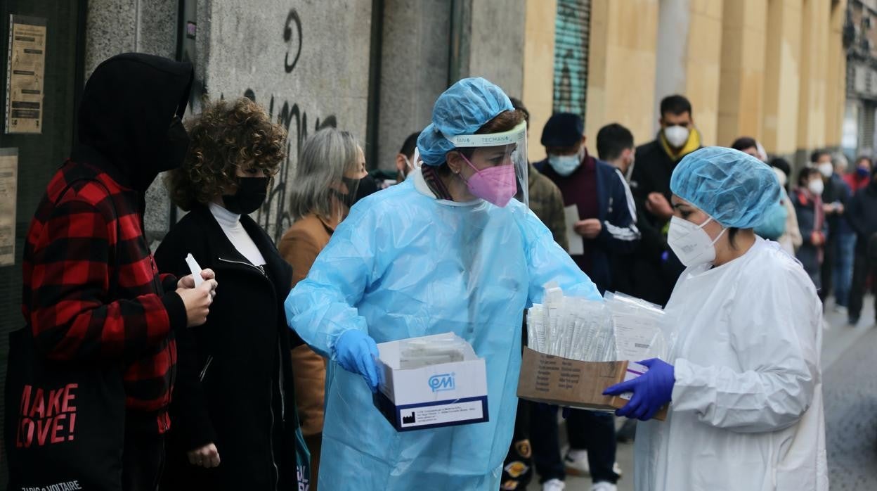 Dos sanitarias recogen test de coronavirus ante la avalancha de personas que hacen cola en un centro de salud