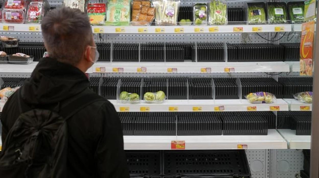 Un hombre observa las estantarerías vacías de un supermercado en el distrito de Sha Tin