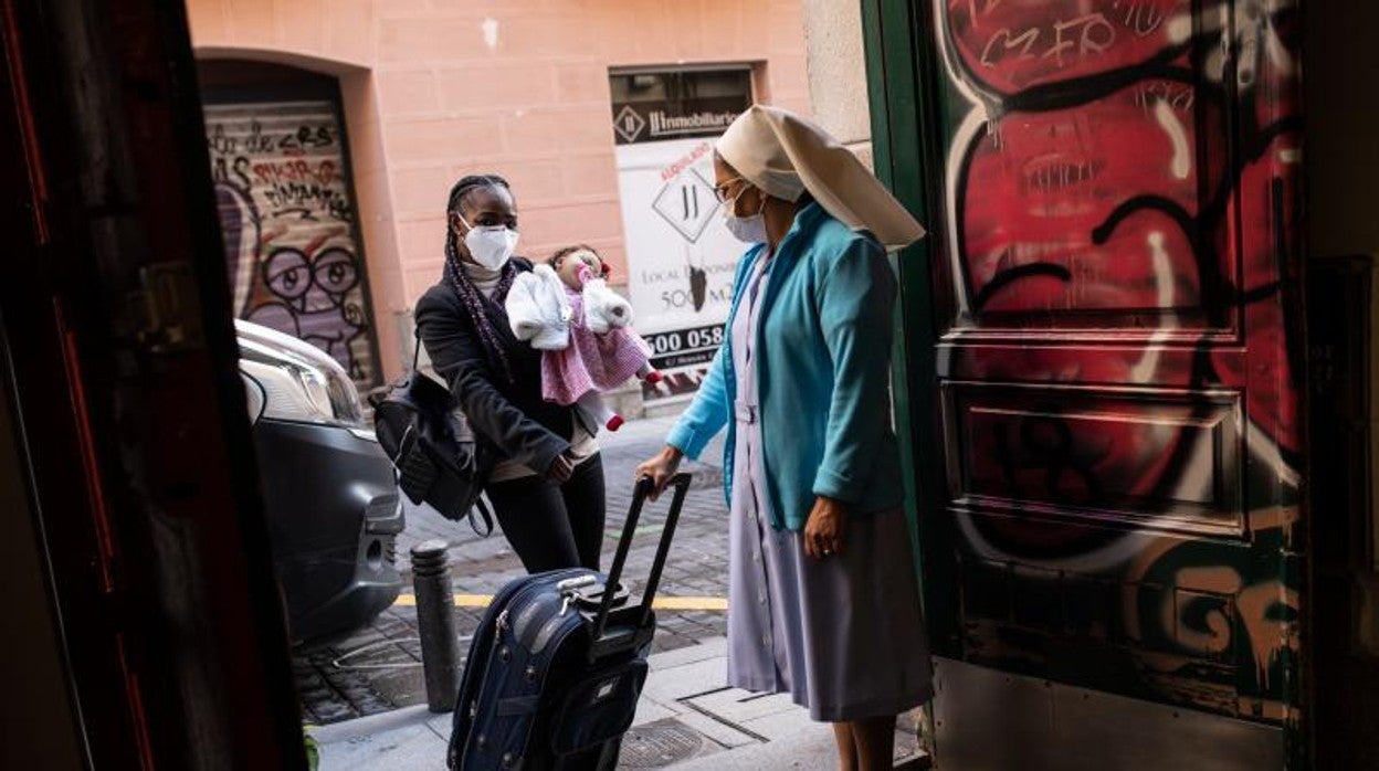 Una mujer con su bebé se acerca a una casa de acogida de Cáritas