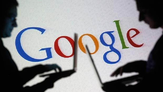 Dos personas trabajan frente a una proyección del logo de Google