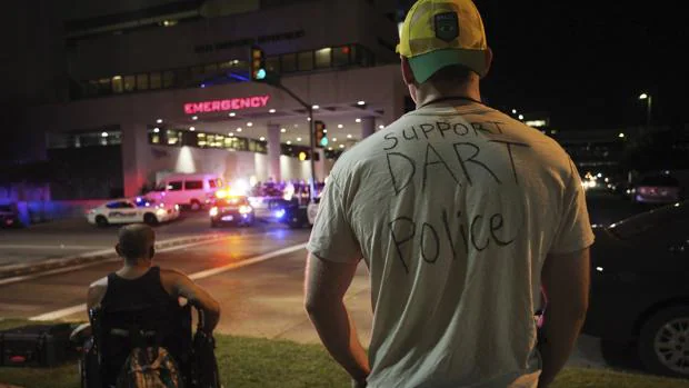 Un hombre luce una camiseta con un mensaje de apoyo a la policía mientras observa la entrada a emergencias del hospital Baylor