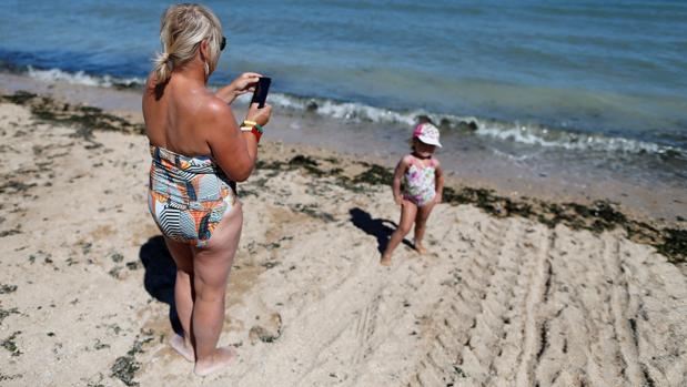 Una mujer fotografía a su hija en la playa