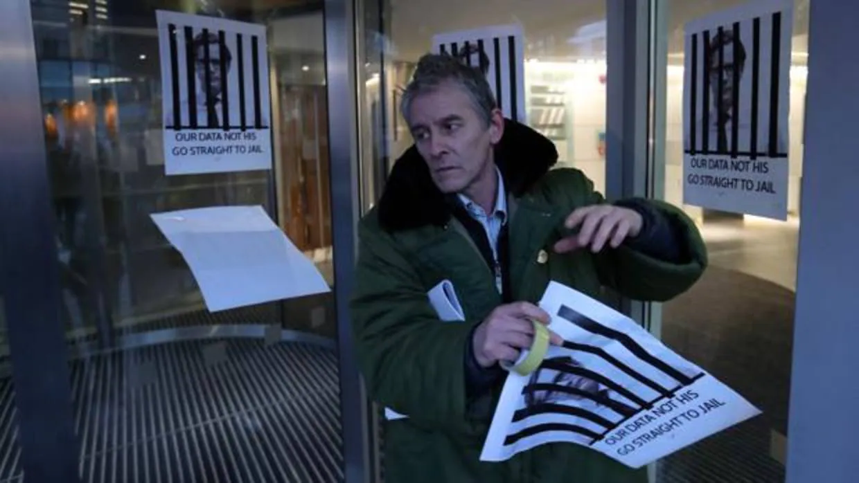 Un hombre pega carteles que muestran al director ejecutivo de Cambridge Analytica, Alexander Nix, tras las rejas, con el lema «Nuestros datos no son suyos. Ve directo a la cárcel»
