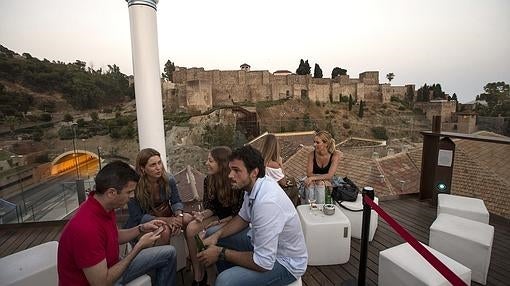 Un grupo de personas disfruta de la terraza del «Alcazaba Premium Hostel» con vistas a la Alcazaba de Málaga