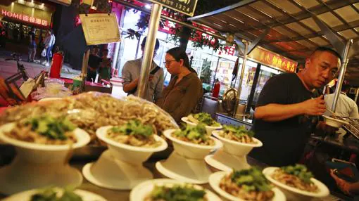 Varias personas compran comida en el antiguo mercado nocturno de Donghuamen, en Pekín