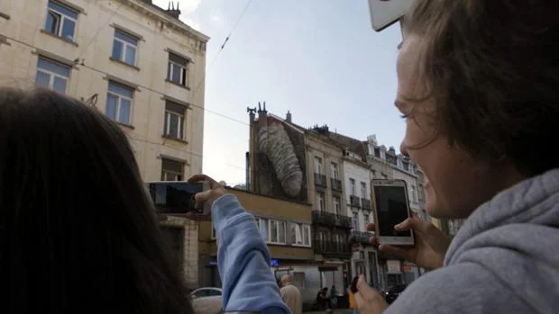Dos personas fotografían uno de los grafitis de alto contenido sexual que han aparecido en Bruselas