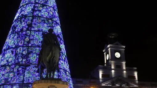 El árbol de la Puerta del Sol iluminado junto al reloj de la plaza
