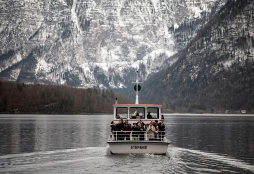 Varios turistas fotografían el paisaje durante una excursión en barco por el lago Hallstatt