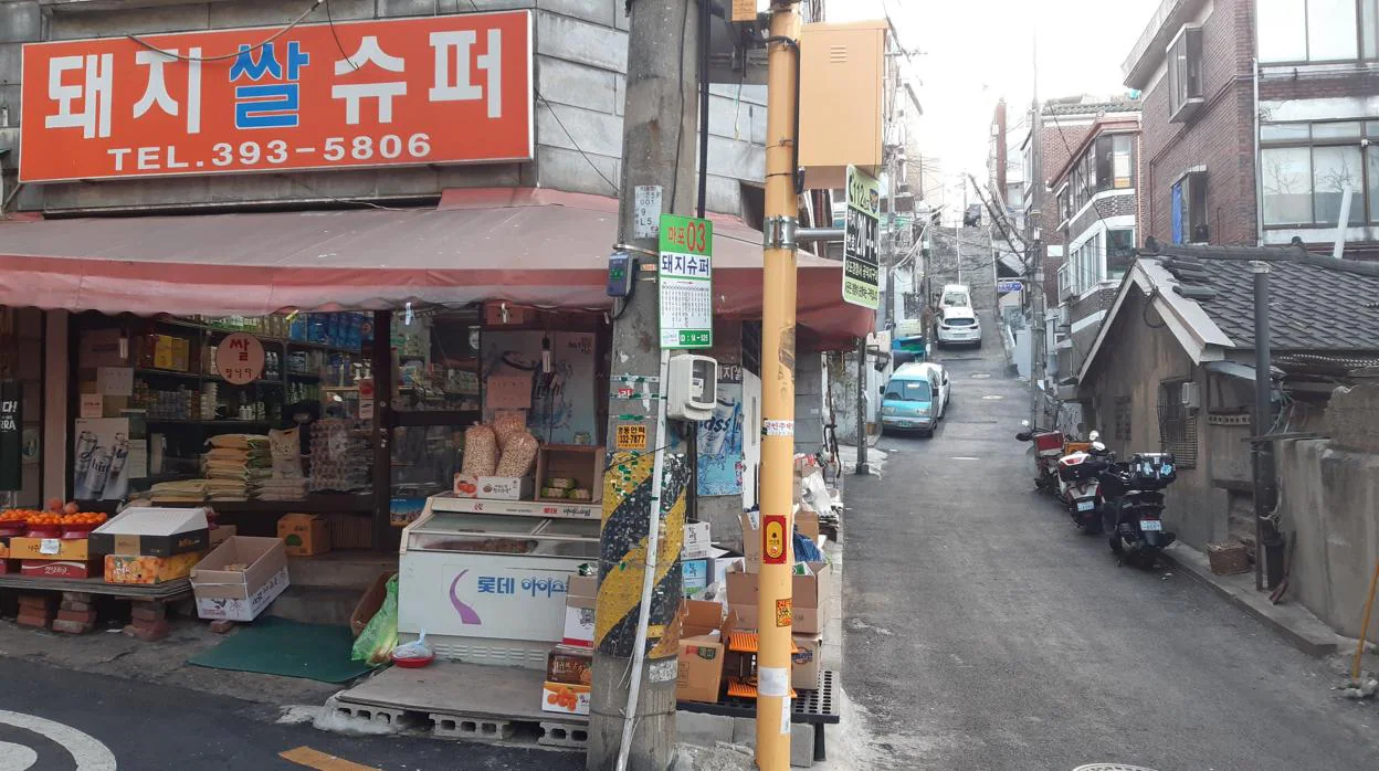 Fotografía de la tienda de alimentación de Kim Kyung-soon, donde se rodó la secuencia en la que los personajes de Ki-woo y Min beben juntos al inicio de la película 'Parasite', con la escalinata al fondo del callejón en la que también se filmó a la familia Kim regresando a casa en pleno aguacero