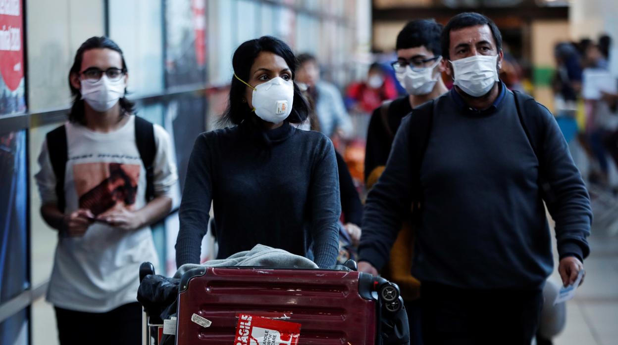 Pasajeros usando mascarillas para evitar la propagación y el contagio del coronavirus este miércoles, en el aeropuerto Arturo Merino Benítez, en Santiago (Chile)