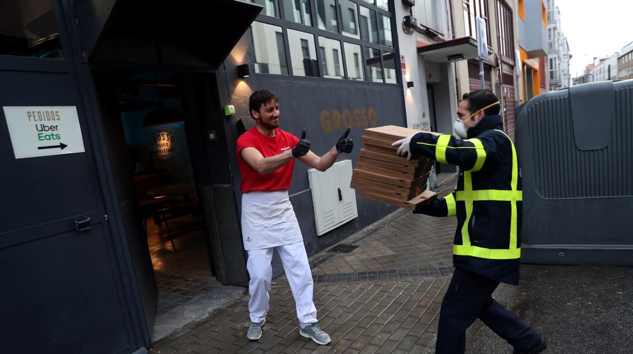 El pizzero Flavio Russo le entrega a José María Carrero Castaño, un repartidor de Correos, algunas de las pizzas destinadas al personal médico de los hospitales