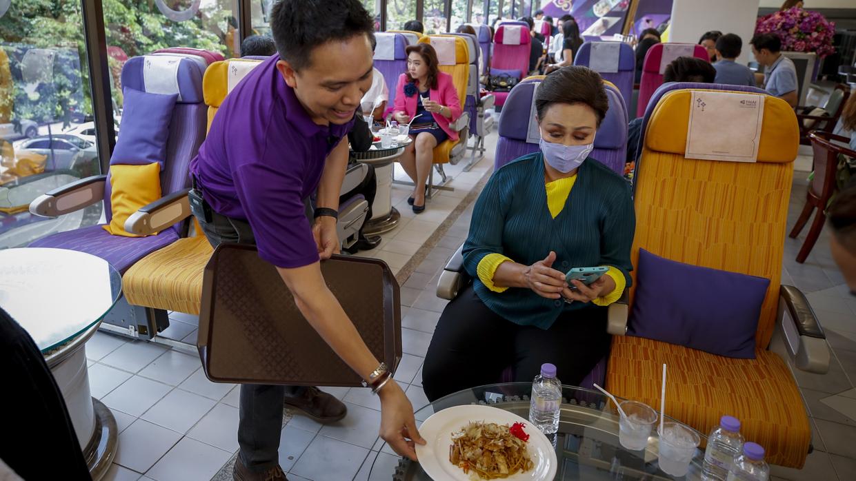 Clientes del restaurante en forma de avión abierto por Thai Airways en Bangkok