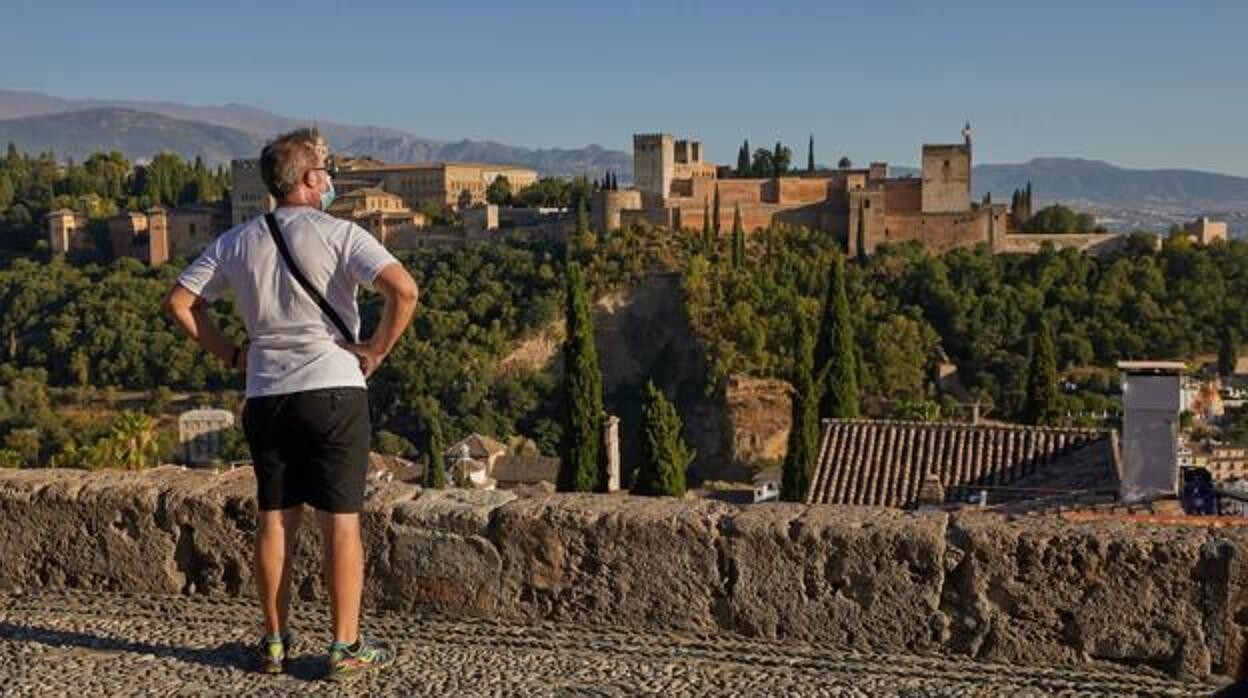 Un turista frente a la Alhambra desde uno de los miradores de la ciudad