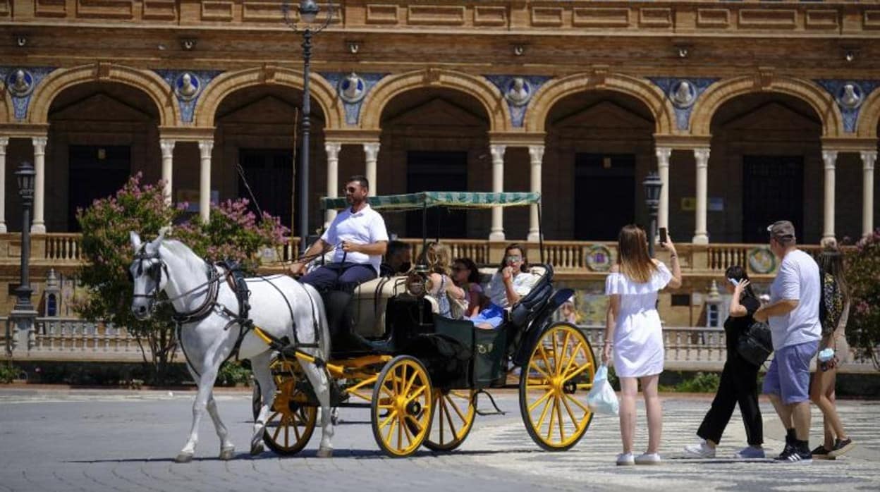 Imagen de un carruaje de caballo con turistas en la Plaza de España de Sevilla