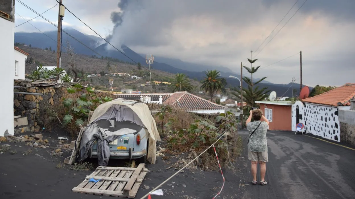 Una turista fotografía el volcán desde una calle cercana al mirador de Tajuya